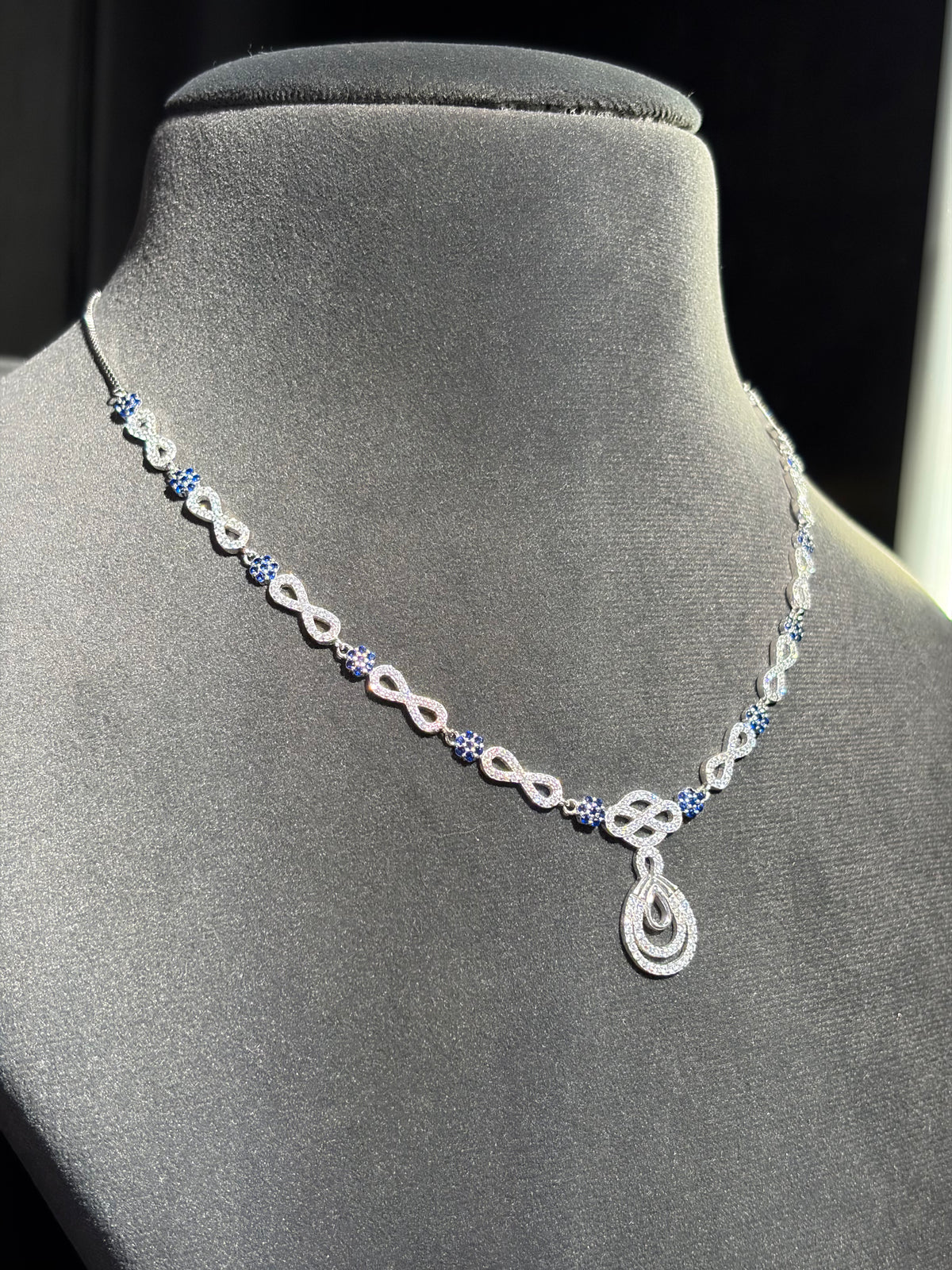 Blue gemstone accents and a teardrop sterling silver pendant